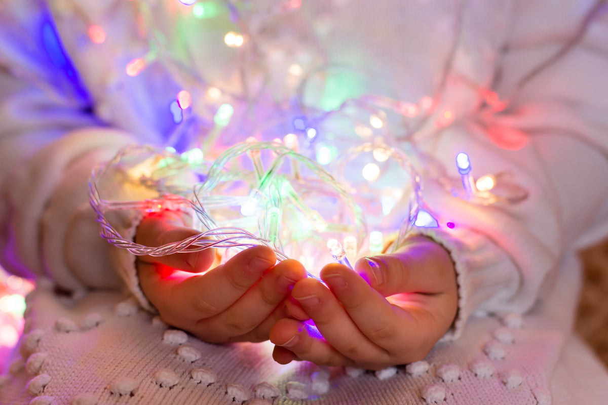 Hands holding colorful LED string lights, illustrating safe connection tips for beautiful holiday lighting and festive home decor.